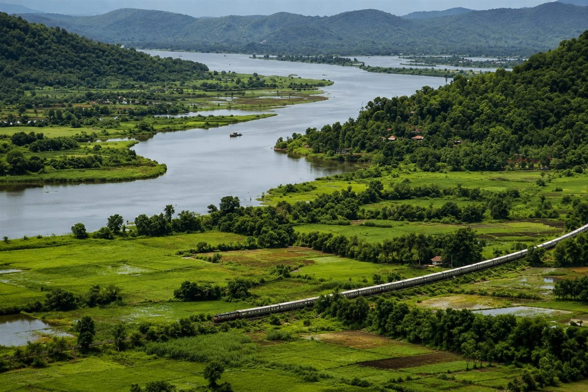 Aerial view of the Konkan Railway train crossing the Vashishti river backwaters, surrounded by green hills